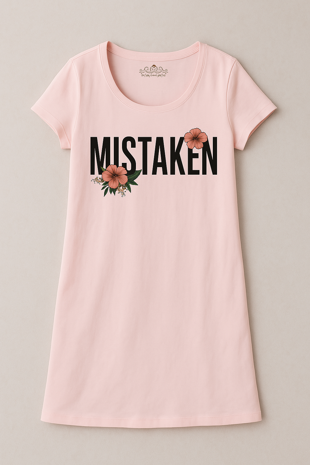 A pink long shirt with the word 'MISTAKEN' printed in black letters on the front, accompanied by a floral design